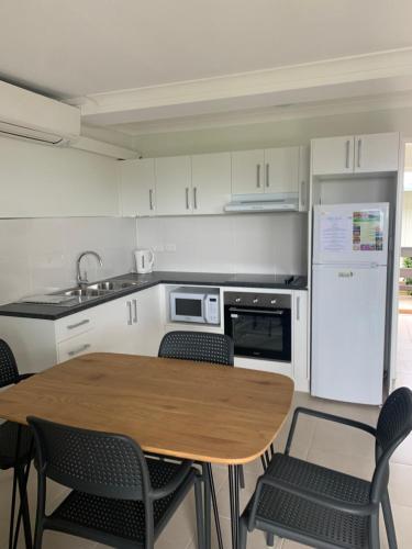 a kitchen with a table and chairs and a microwave at Airlie Beach Apartments in Airlie Beach