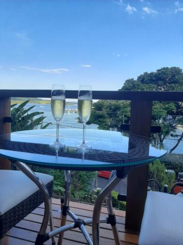 two glasses of wine sitting on a table on a balcony at Solarium de Escarpas Suítes in Capitólio