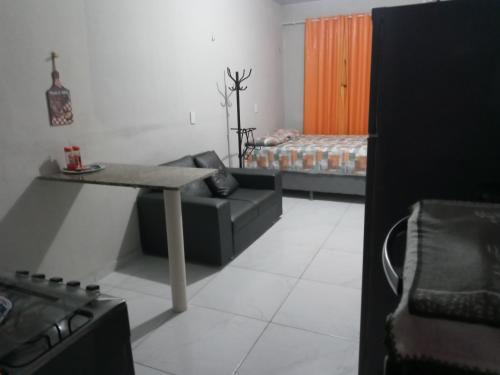 uma sala de estar com um sofá, uma mesa e uma cama em Kitnet mobiliado, confortável e bem localizado. em Fortaleza