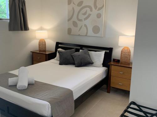 um quarto com uma cama com duas mesas de cabeceira e dois candeeiros em Airlie Beach Apartments em Airlie Beach