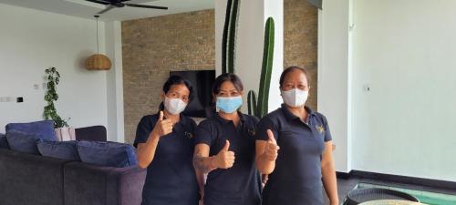 three women wearing masks giving the thumbs up at Villa Mimpi Bali in Jimbaran
