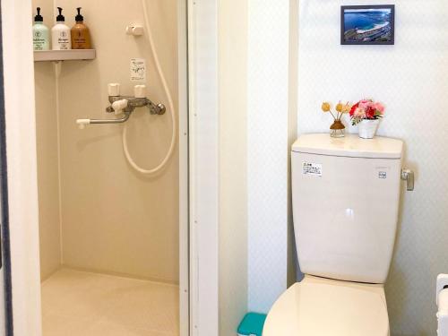 a bathroom with a toilet with flowers on top of it at Pension Marinetown Aratta Vacation STAY 13299 in Yonabaru