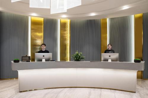 two people sitting at a reception desk with laptops at Atour Hotel Hotan Unity Plaza in Hoten