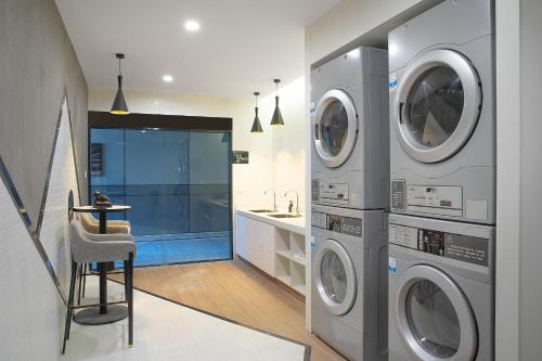 a laundry room with two washing machines and a stool at Atour Hotel Hotan Unity Plaza in Hoten