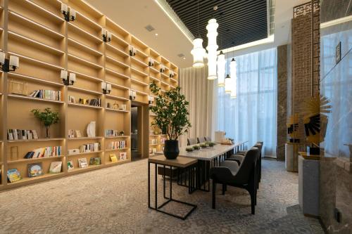 een bibliotheek met een tafel en stoelen en boekenplanken bij Atour Hotel Zhangjiajie Tianmen Mountain in Zhangjiajie
