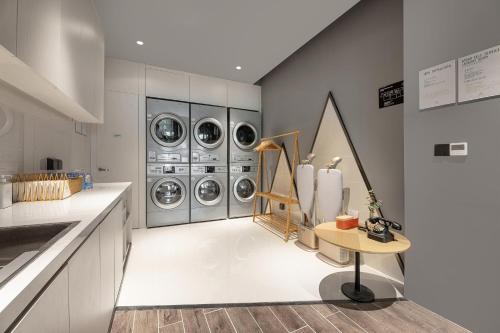 a laundry room with four washer and dryers at Atour Hotel Qingdao Jiaodong International Airport in Jiaozhou