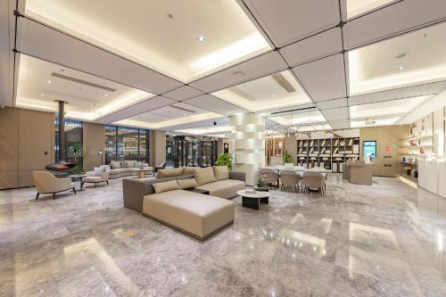 a lobby with a couch and tables and chairs at Atour Hotel Huai an Suning Plaza Dazhi Road in Huai'an