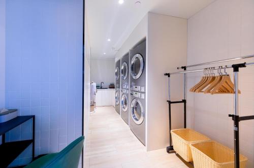 a laundry room with three washer and dryer machines at Atour Hotel Sanhe Yanjiao Development District in Sanhe