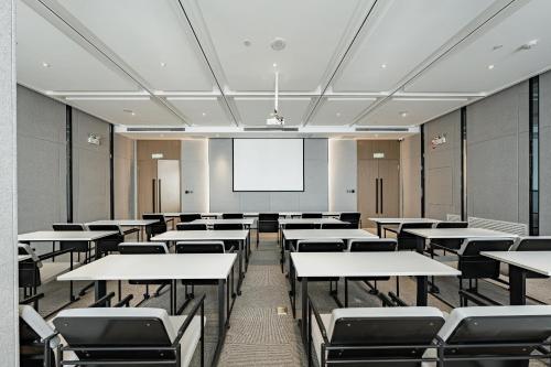an empty classroom with tables and chairs and a projection screen at Atour Hotel Urumqi Zhongyinggong South Beijing Road in Ürümqi
