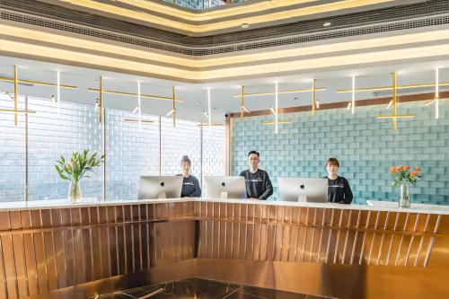 three people sitting at a counter with their laptops at Atour Hotel Kunshan Baoyu Plaza North Changjiang Road in Kunshan