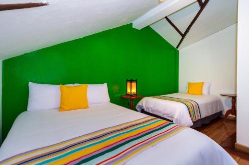 a green room with two beds and a green wall at Hotel Posada del Rey in Cuenca