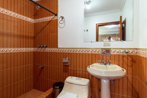 a bathroom with a sink and a toilet and a mirror at Hotel Posada del Rey in Cuenca