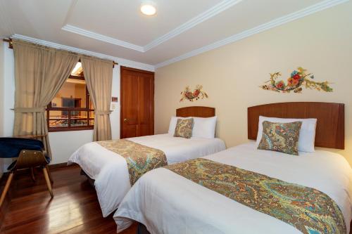 a hotel room with two beds and a window at Hotel Posada del Rey in Cuenca