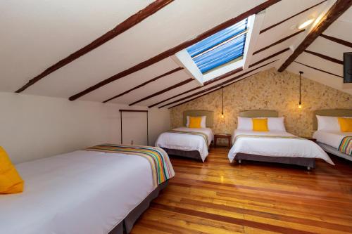 a attic room with three beds and a window at Hotel Posada del Rey in Cuenca