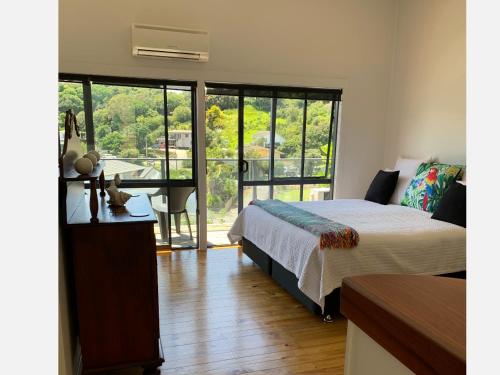 a bedroom with a bed and a desk with a view at PACIFIC PARADISE COTTAGE in Tutukaka