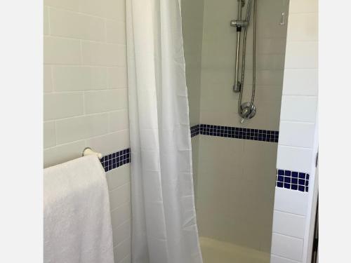 a bathroom with a shower with a white shower curtain at PACIFIC PARADISE COTTAGE in Tutukaka