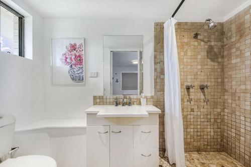 a white bathroom with a sink and a shower at Lovely 2bd Unit, Patio and views. Best weekly rate in Alexandra Headland