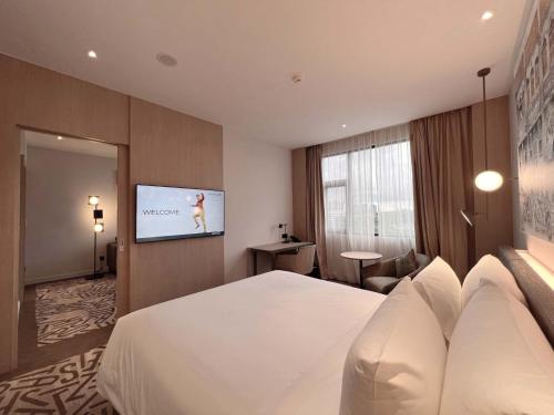 a hotel room with a bed and a flat screen tv at Mercure Kuala Lumpur Glenmarie in Shah Alam