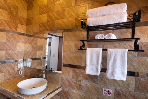 baño con lavabo y toallas en la pared en Hotel Hacienda Cusco Centro Historico, en Cusco