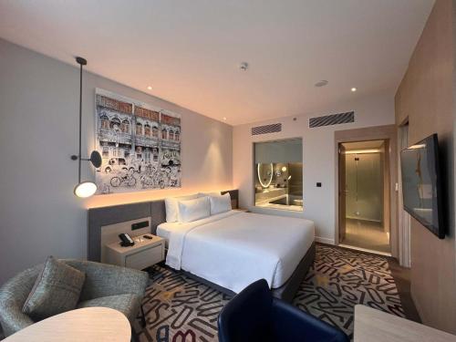 a hotel room with a white bed and a couch at Mercure Kuala Lumpur Glenmarie in Shah Alam