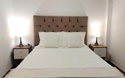 a bedroom with a large white bed with two lamps at APARTAMENTOS PRIVADOS a 10 minutos del AEROPUERTO Jorge Chávez Lima in Lima