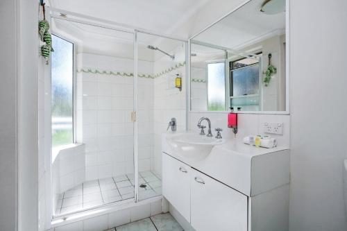 a white bathroom with a sink and a shower at Riviera Noosa Resort in Noosaville