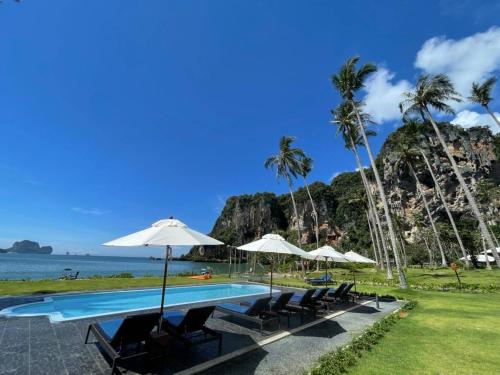 a pool with chairs and umbrellas next to the ocean at Tinidee Hideaway Tonsai Beach Krabi - SHA Extra Plus in Tonsai Beach