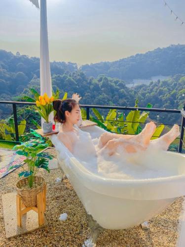 a woman laying in a bath tub on a balcony at Phu Morinn Cafe &Camping Monjam in Mon Jam