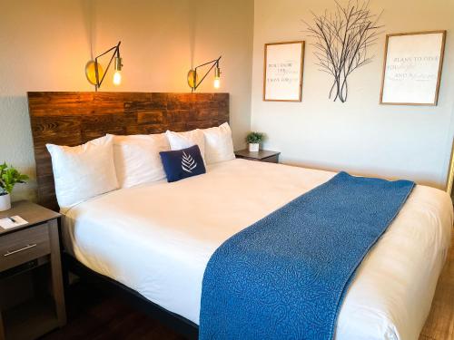 a bedroom with a large white bed with a blue blanket at PINEMARK Inn Suites Events in Saint Clair