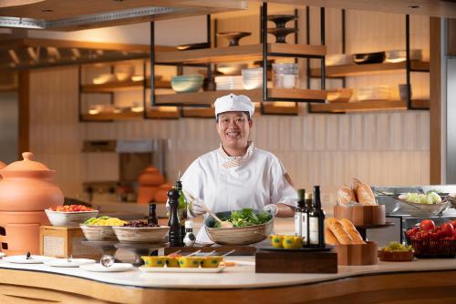 a chef standing in a kitchen preparing food at Melia Chiang Mai in Chiang Mai