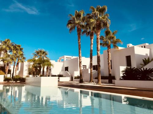 een zwembad met palmbomen en witte gebouwen bij Flamingo Mojácar in Mojácar