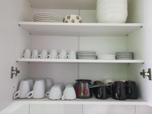 a cupboard filled with white and black cups and plates at Stan u centru Prnjavor in Prnjavor