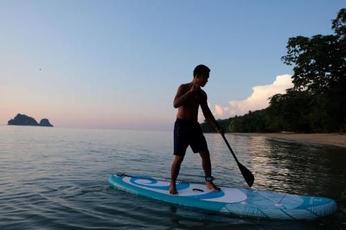 a man standing on a paddle board in the water at Touch Glamping Koh Yao Noi ทัช แกรมปิ้ง เกาะยาวน้อย in Ko Yao Noi