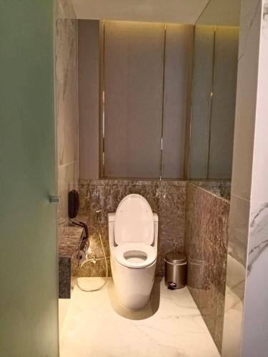 a bathroom with a white toilet in a stall at Asawin Grand Convention Hotel in Bangkok