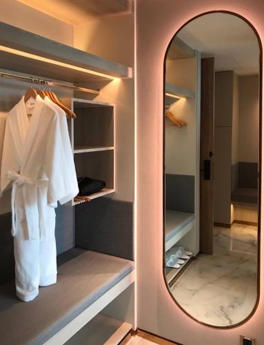 a mirror in a walk in closet with a white robe at Asawin Grand Convention Hotel in Bangkok