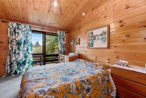 a bedroom with a bed in a wooden room at Rutherfurd Lakehouse - Taupō Holiday Home in Taupo