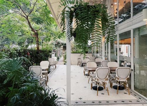 a patio with chairs and tables in a building at 6號花園別墅酒店 Shenzhen No'6 Garden Villa --French Window with garden view,Close to Sea World &Shekou Ferry Port &K11 Ecoast &Subway Nearby ,Offer Western food and coffee &English speaking with tour services in Shenzhen