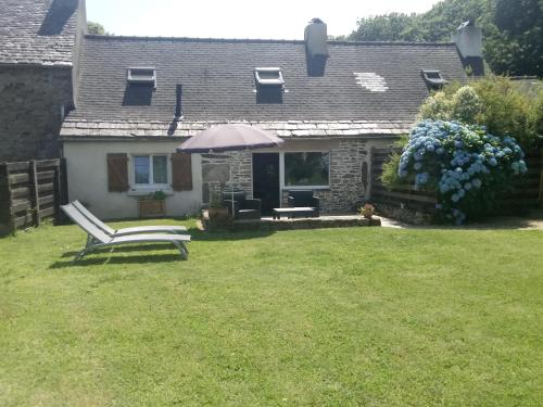 une maison avec une chaise et un parasol dans la cour dans l'établissement Petite maison dans les Monts d'Arrée TY COZ, à Commana