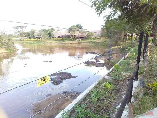 a body of water with a fence and a river at Mara River Lodge in Aitong
