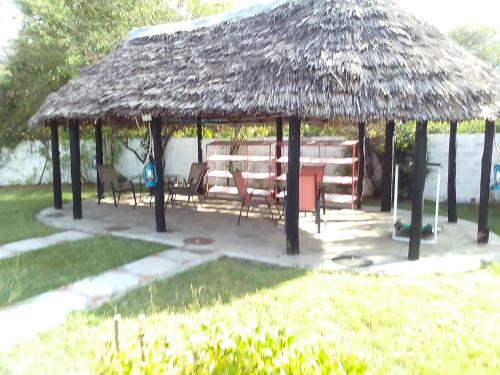 a hut with a table and chairs in a yard at Mara River Lodge in Aitong