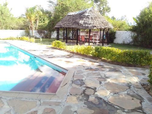 a swimming pool with a gazebo next to a yard at Mara River Lodge in Aitong