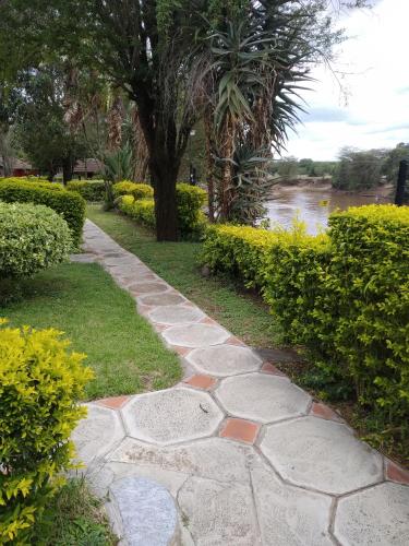 a stone walkway next to a river with a tree at Mara River Lodge in Aitong