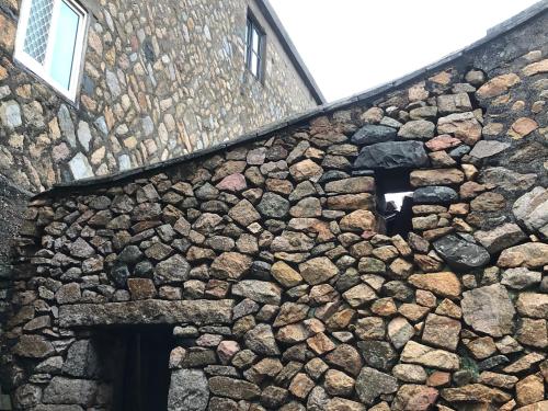 a stone building with two windows on it at Horn Seaside Homestay in Nangan