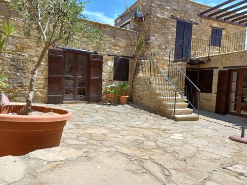 a stone courtyard with a building with a staircase at Kleanthis House in Tochni
