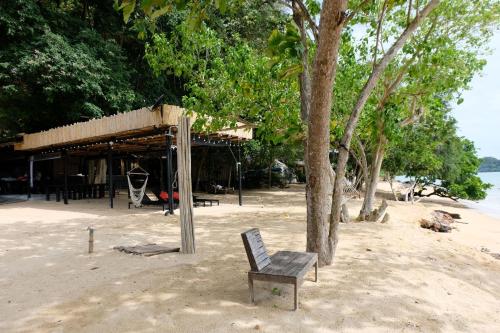 a chair sitting next to a tree on a beach at Touch Glamping Koh Yao Noi ทัช แกรมปิ้ง เกาะยาวน้อย in Ko Yao Noi