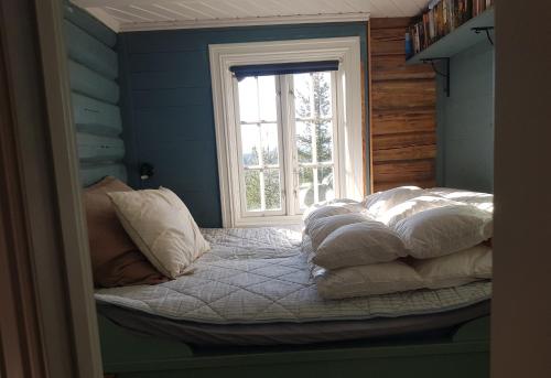 um quarto com uma cama com almofadas e uma janela em Fredelig plass for rekreasjon em Krøderen