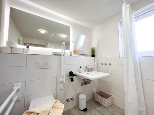 Kapitaenshaus-Lassen-Zimmer-Atlantis في فيسترلاند: حمام أبيض مع حوض ومرآة