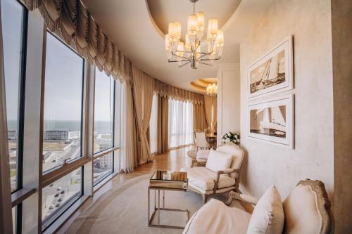a living room with a chandelier and large windows at Qafqaz Sahil Hotel Baku in Baku