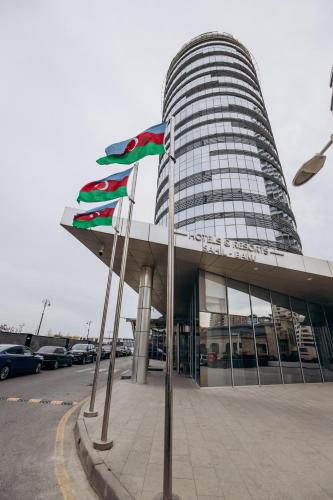 a building with several flags in front of it at Qafqaz Sahil Hotel Baku in Baku