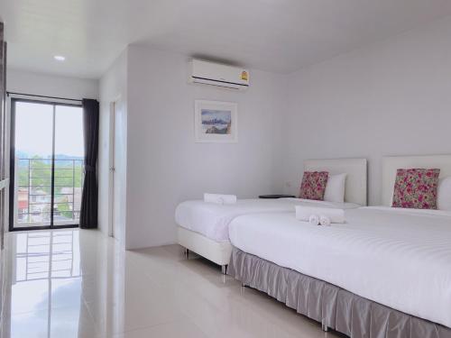 two beds in a white room with a window at Momda Resort @Ranong in Ranong